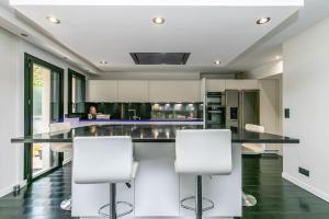 a kitchen with a black counter and white chairs at Villa, centre-ville, Paris, Disneyland, Ascenseur, Parkings in Nogent-sur-Marne