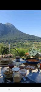 a table with food on it with a view of a mountain at Canerbey Çiftlik in Ovacık