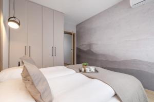 a bedroom with a white bed and a wall at Bright Apartment in Kraków with Garden, Air Conditioning, Parking and Desk by Renters Prestige in Kraków