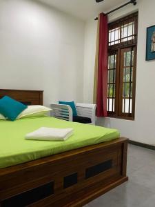Un dormitorio con una cama con sábanas verdes y una ventana en Cinnamon Apartment Panadura 2, en Panadura