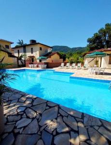 ein großer blauer Swimmingpool mit Stühlen und ein Haus in der Unterkunft Casa de condomínio 900m da Praia de Boiçucanga in São Sebastião