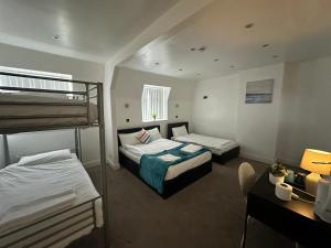 um quarto de hotel com duas camas e uma secretária e uma cama em Olive Lodge Blackpool em Blackpool
