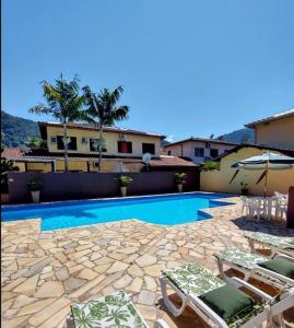 einen Pool mit zwei Liegestühlen und einem Sonnenschirm in der Unterkunft Casa de condomínio 900m da Praia de Boiçucanga in São Sebastião