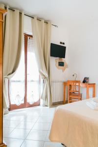 1 dormitorio con 1 cama y una ventana con cortinas en La Marmora en Alguer
