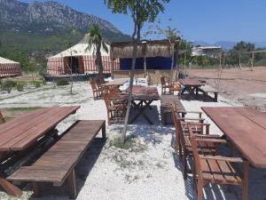 um grupo de mesas e cadeiras de madeira com uma tenda em Adrasan Yıldız Bungalow Tatil Köyü em Adrasan
