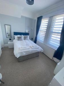 a bedroom with a large white bed and windows at Seaview Sanctuary in Eastbourne