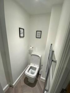 a bathroom with a toilet with two pictures on the wall at LT Apartments 56 - Free St parking in Leicester