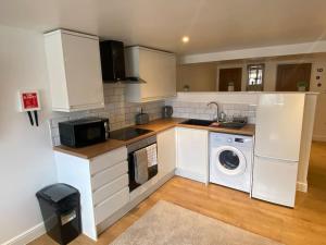 a kitchen with white cabinets and a washing machine at Kings Lets - Studio Apartment in Leicester +6 photos