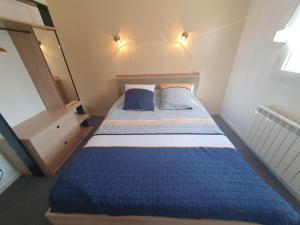 - une petite chambre avec un lit bleu et 2 oreillers dans l'établissement Chez Pomy, à Cransac