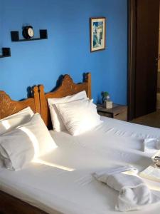 een wit bed met witte kussens en een blauwe muur bij Οrantes Maris Family And Groups in Katápola