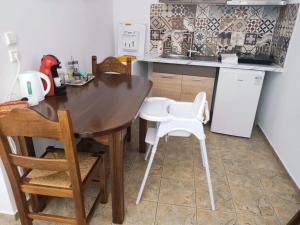 a kitchen with a wooden table and white chairs at Οrantes Maris Family And Groups in Katapola