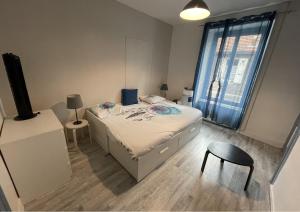 um pequeno quarto com uma cama e uma cadeira em Bienvenu chez Zazou em Limoges
