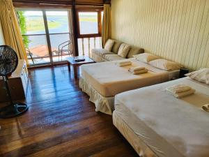 a room with two beds and a living room with a window at Boulevard 251 Riverside Apartments in Iquitos