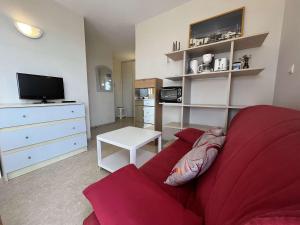 ein Wohnzimmer mit einem roten Sofa und einem TV in der Unterkunft Appartement Rochefort, 2 pièces, 4 personnes - FR-1-246B-51 in Rochefort