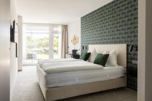ein Schlafzimmer mit einem großen Bett und einer Wand mit grünen Akzenten in der Unterkunft zum Sausaler - Boutique Hotel-Pension Südsteiermark in Sankt Nikolai im Sausal