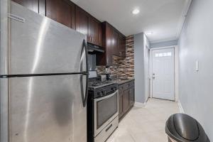 a kitchen with a stainless steel refrigerator and wooden cabinets at MODERN Updated Rare 2BR Condo in Washington, D.C.