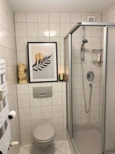 ein Badezimmer mit einer Dusche und einem WC sowie ein Bild in der Unterkunft Retro Sky View in Bahnhofsnähe in Waiblingen