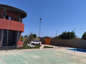Villa Mostafa Sadek, Swimming pool, Tennis & Squash - Borg ElArab Airport Alexandria في برج العرب: موقف للسيارات مع ملعب تنس أمام المبنى