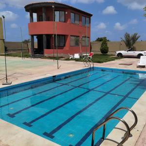 a swimming pool in front of a house at Villa Mostafa Sadek, Swimming pool, Tennis & Squash - Borg ElArab Airport Alexandria in Borg El Arab