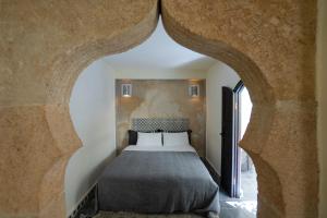 ein Schlafzimmer mit einem Bett in einem Zimmer mit einem Torbogen in der Unterkunft Riad Dar Nor in Essaouira