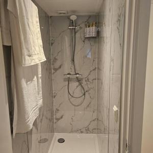 uma casa de banho com um chuveiro e uma parede em mármore. em One bedroom apartement with terrace and wifi at Lisse em Lisse