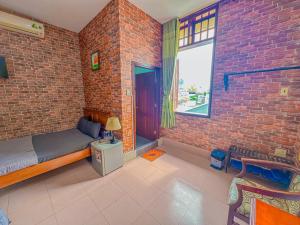 een slaapkamer met een bakstenen muur, een bed en een raam bij Hoàng Sơn's Home in Can Tho