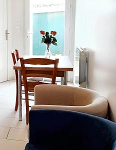 a table and a chair with a vase of flowers on it at Maison d'une chambre avec jardin clos et wifi a Tonnay Charente in Tonnay-Charente