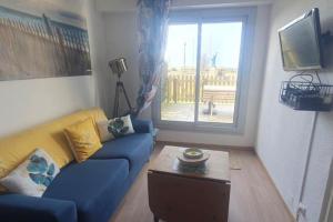 sala de estar con sofá azul y mesa en Appartement front de mer - 6198, en Soulac-sur-Mer