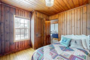a bedroom with a bed with wooden walls and a window at Winnisquam Sunrise in Sanbornton