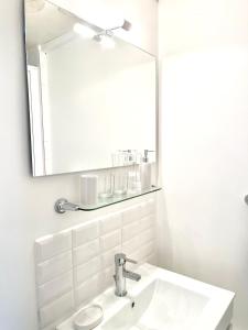 a white bathroom with a sink and a mirror at Le Manoir des Doyens in Bayeux