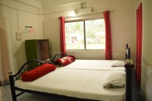 2 Einzelbetten in einem Zimmer mit Fenster in der Unterkunft Dooars Nest Resort Rahutbari in Chālsa Mahābāri