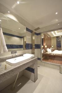 Grand Him Queen AC Centralized في دارامشالا: حمام مع حوض ومرآة كبيرة