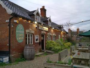 a brick building with a sign and lights on it at The Half Moon Inn Rushall IP21 4QD in Pulham Saint Mary the Virgin
