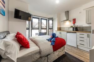 a bedroom with a bed with red pillows and a kitchen at Stay Sleep Rest - Derby Road in Nottingham