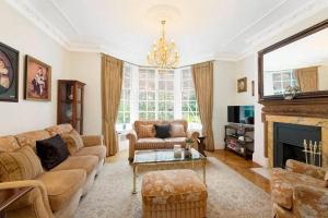uma sala de estar com um sofá e uma lareira em Promient Royal Victorian Villa - Sleeps 12 em Londres
