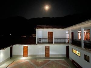 una casa con balcón por la noche con la luna en Hotel Restaurante Minas Cocha, en Chavín de Huantar
