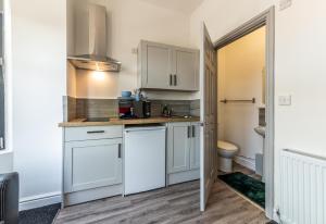 a kitchen with white cabinets and a toilet at Stay Sleep Rest - Derby Road in Nottingham