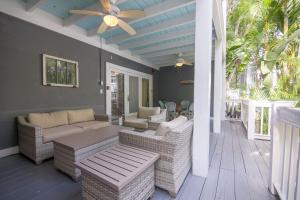 a porch with wicker furniture and a ceiling fan at Ambrosia Key West in Key West