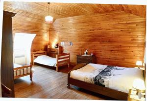 a bedroom with two beds and a wooden wall at Maison confortable avec vue sur la montagne à Le Fau in Le Fau