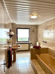 a bathroom with a tub and a sink and a window at Pension 1595 im Weingut Botzet in Maring-Noviand