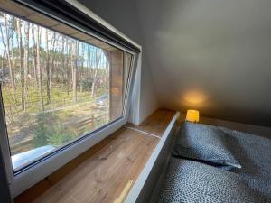 Cette petite chambre dispose d'une grande fenêtre avec un lit et un siège de fenêtre. dans l'établissement Sunny Home Turawa, à Turawa
