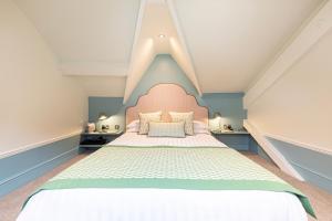 a bedroom with a large bed with a pink headboard at Escape Boutique B&B in Llandudno