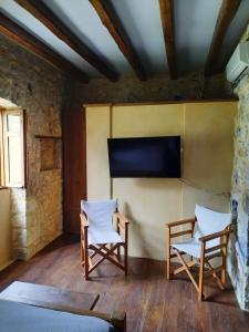 a room with two chairs and a flat screen tv at Studio Tsiliviani in Loukádhika