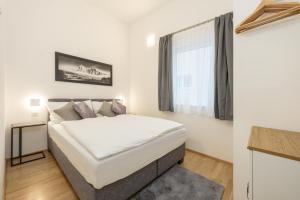 a white bedroom with a bed and a window at Appartement Tamino - City Appartement by Schladmingurlaub in Schladming