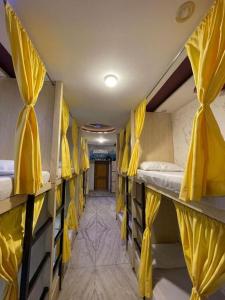 a room with several bunk beds with yellow curtains at Monkey Travel Hostel in Agra