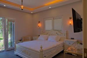 1 dormitorio con 1 cama blanca y TV en Vahide Homes, en Doger Koyu