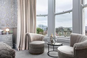 a living room with two chairs and a table and a window at Escape Boutique B&B in Llandudno