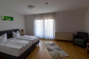 a bedroom with a bed and a chair and a window at Hotel Landgasthaus Rössle in Hofweier +1 photo