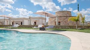 a villa with a swimming pool in front of a building at Borgo Specchia Natural Resort in Specchia
