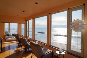 a living room with chairs and large windows at Nesaki Native in Hakodate